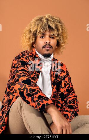 Stock Foto von stilvollen Afro Mann Blick auf die Kamera im Studio vor braunem Hintergrund aufgenommen. Stockfoto
