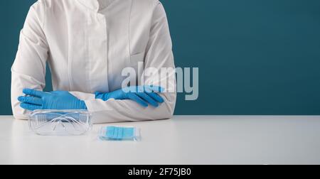 Eine Krankenschwester in einem weißen Mantel sitzt bei einem Impftermin auf blauem Hintergrund. Stockfoto