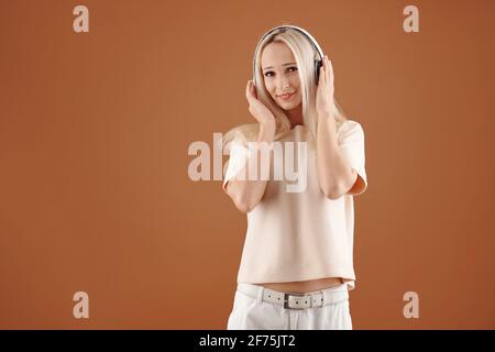 Glückliche junge Frau in lässigen Kleiden, die gerne Musik hören In Kopfhörern Stockfoto