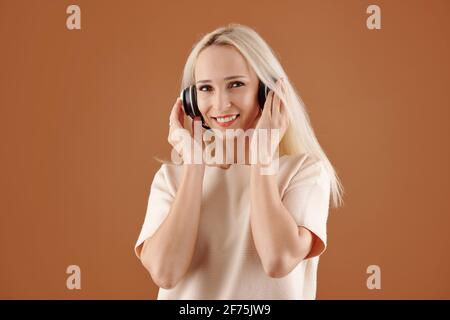 Porträt einer ziemlich lächelnden jungen Frau, die gerne Musik hört In Kopfhörern Stockfoto