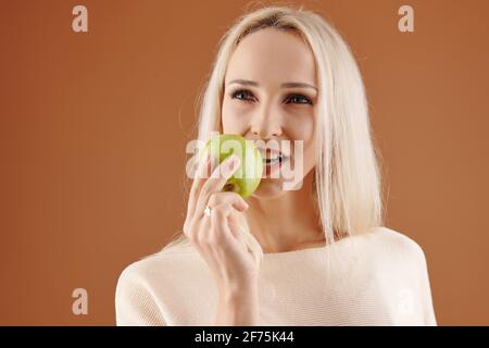 Nachdenklich hübsche junge Frau beißt saftigen grünen Apfel Stockfoto