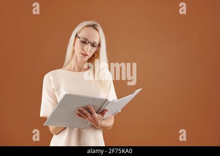 Serious ziemlich weibliche Lehrerin lesen Dokument in Zwischenablage und nehmen Notizen Stockfoto