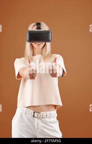Porträt einer glücklichen, aufgeregt jungen Frau in einer Virtual-Reality-Brille Daumen hoch Stockfoto