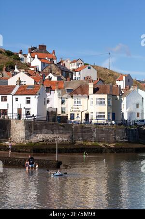 Sonnige Sommeransicht der dicht bepackten traditionellen Hütten, die sich aus dem Hafen in Staithes, Yorkshire Coast, erheben Stockfoto