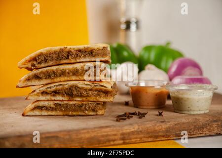 Gefülltes Hackfleisch qeema naan mit würzigen Saucen und Zutaten Stockfoto