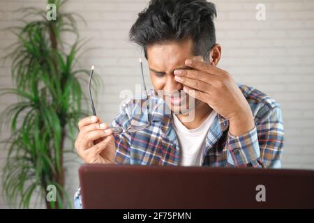 Nahaufnahme von verärgerten Mann, der unter starken Augenschmerzen leidet Während der Arbeit an einem Laptop Stockfoto