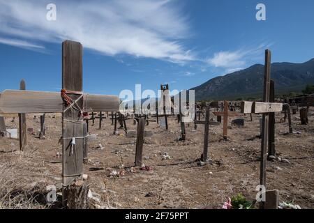 Der historische Taos Pueblo Friedhof in New Mexico mit verwitterten Holzkreuzen, die die Gräber der indianischen Gemeinde markieren. Stockfoto