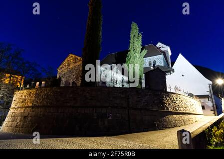 Eine wunderschöne dramatische Aufnahme aus dem niedrigen Winkel einer katholischen Kirche auf dem Friedhof in der Nacht. Selektive Fokusmethode. Stockfoto