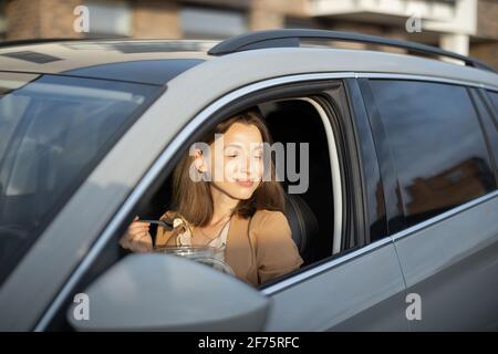 Schöne Frau, die im Auto einen heidnischen Salat isst. Ich habe eine Bestellung zum Essen erhalten. In der Mittagspause haben Sie einen schnellen Snack. Stockfoto