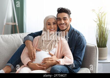 Millennial Muslim Paar erwartet EIN Baby und entspannt sich zusammen auf der Couch zu Hause Stockfoto