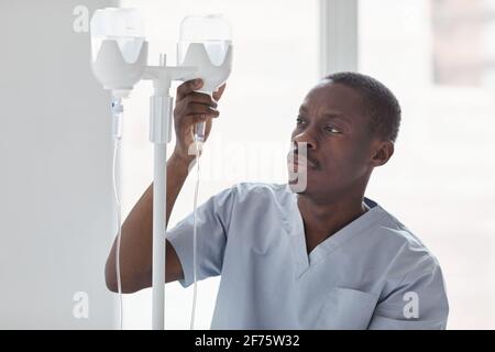 Porträt eines afroamerikanischen Krankenpflegers, der während der Behandlung von Patienten im Krankenhaus eine Infusionsstelle eingerichtet hat Stockfoto