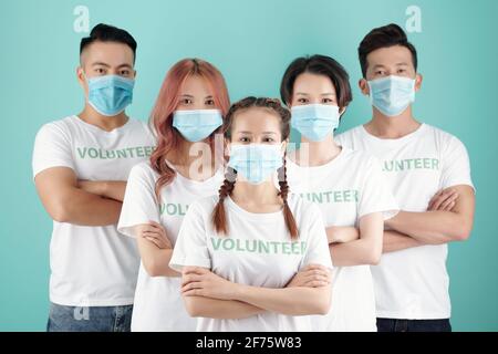 Team von jungen vietnamesischen Freiwilligen in Schutzmasken hinter stehen Ihre weibliche Führerin Stockfoto