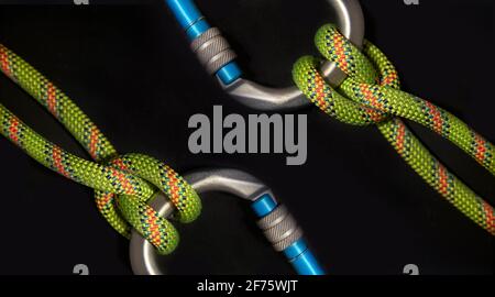 Inverse Karabiner mit Schifferknoten und fluoreszierendem grünen Seil Ein schwarzer Hintergrund Stockfoto