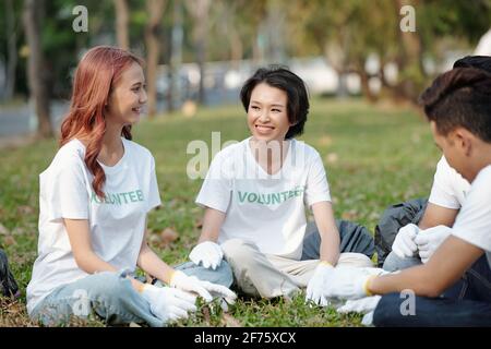 Junge Freiwillige, die sich nach dem Aufheben im Park auf Gras ausruhen Müll im lokalen Park Stockfoto