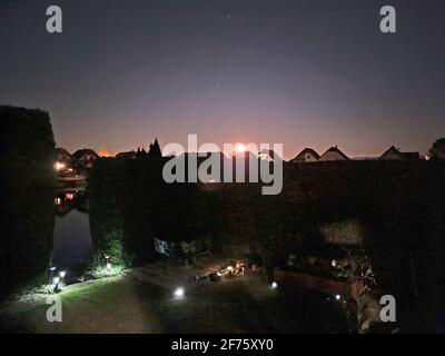 Vollmond, der über einer kleinen Siedlung auf einem See aufgeht In niederösterreich Stockfoto