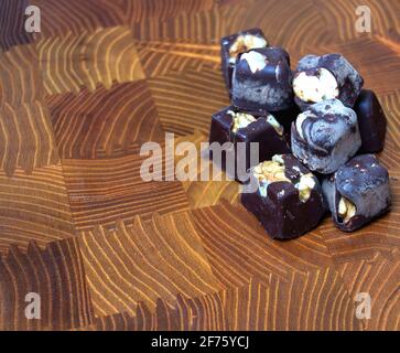 Dunkle Schokolade mit Mandeln und Nüssen auf einem Holzhacken Platine Stockfoto