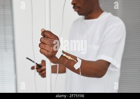 Nahaufnahme eines afroamerikanischen Mannes im Krankenhauszimmer, Fokus auf der Hand mit infusionsaufbau, Kopierbereich Stockfoto
