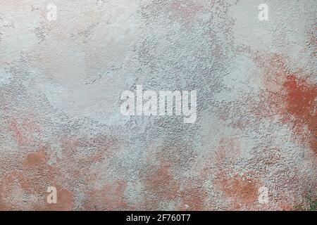 Der Hintergrund ist eine schmutzige Wand. Flecken und rote Streifen auf dem alten strukturierten Putz der Wand. Stockfoto