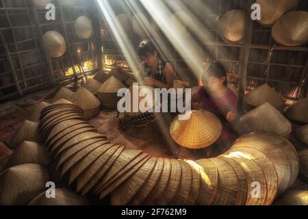 Zwei vietnamesische Schwestern Handwerker machen den traditionellen vietnam Hut in dem alten traditionellen Haus in AP Thoi Phuoc Dorf, Hochiminh Stadt, Vietnam, tr Stockfoto