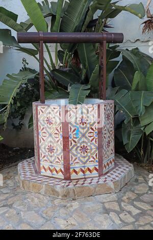 Ein farbenfrohes Keramikkunstwerk eines Wasserbrunnen in einer grünen Ecke in Estepona in Spanien Stockfoto