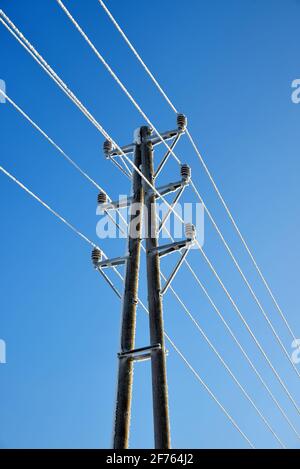 Gefrorener elektrischer Pylon. Sendeturm mit blauem Himmel im Hintergrund. Stockfoto