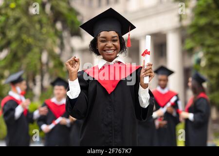 Fröhliche afroamerikanische junge Dame im Abschlusskostüm Stockfoto