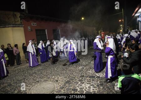 Cucuruchos in lila Gewändern werden feierlich durch die Straßen von Antigua, Guatemala, während der traditionellen Feierlichkeiten der Weihnachtsfeier in der Karwoche Semana gefeiert. Stockfoto