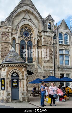 Staycation. Im Turret Grill Restaurant können sich die sprechenden Damen und die Leute an den Tischen draußen unter Sonnenschirmen essen. Das Rathaus von Hastings im Hintergrund. Stockfoto