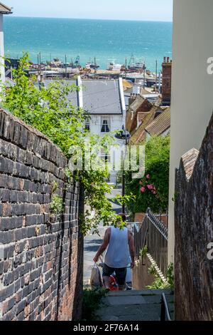 Staycation Idee. Ein Mann geht die Stufen hinunter, die vom West Hill zur Altstadt von Hastings führen. Slade Beach und der englische Kanal im Hintergrund Stockfoto