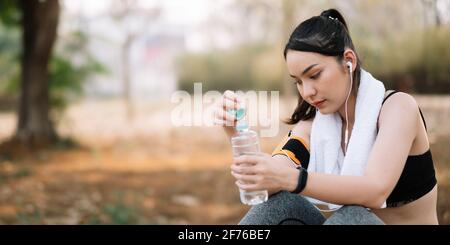 Athletische asiatische Frau, die sich nach einem harten Training in den Bergen bei Sonnenuntergang ausruhte. Sportliche Tight-Kleidung Stockfoto