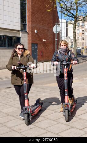 Zwei junge Frauen testen VOI E-Scooter im Stadtzentrum von Bristol. Stockfoto