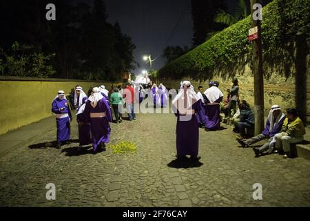 Cucuruchos in lila Gewändern werden feierlich durch die Straßen von Antigua, Guatemala, während der traditionellen Feierlichkeiten der Weihnachtsfeier in der Karwoche Semana gefeiert. Stockfoto