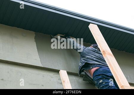 Dnepropetrovsk, Ukraine - 03.30.2021: Fassadenarbeiter, der die Außenwand des Gebäudes verputzt. Stockfoto