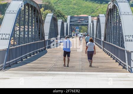 Regua / Portugal - 10/02/2020 : Blick auf ein älteres Paar Touristen auf dem Rücken, der durch die metallische Brücke der Stadt Peso Regua schlendert Stockfoto