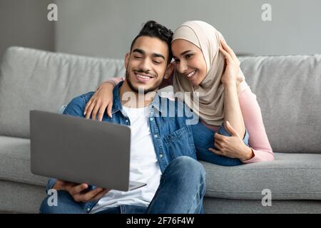Glückliches Paar aus dem Nahen Osten, das im Internet nach neuen Möbeln für zu Hause sucht Stockfoto