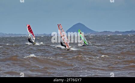 Portobello, Edinburgh, Schottland, UK Wetter. April 2021. Windsurfer genießen die herausfordernden Bedingungen von NW-Winden 31 km/h mit potenziellen Böen von 49 km/h. Ungewöhnlich für Porty, aber diese Leute aus Edinburgh konnten nicht nach Longniddry reisen, da die Lockdown-Einschränkungen von „Stay Local“ nicht möglich waren. Im Bild: Die drei Amigos am Firth of Forth mit Berwick Law in East Lothian im Hintergrund. Stockfoto