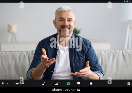 Fröhlicher, gereifter Mann, der von zu Hause aus eine Videokonferenz abhalten kann Stockfoto
