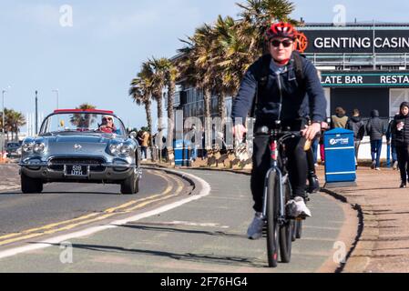 Southend on Sea, Essex, Großbritannien. April 2021. Der Osterfeiertag Montag hat sich in einen sonnigen, aber kühlen Nachmittag, mit einem starken kühlen Wind. Chevrolet Corvette C1 Oldtimer und Radfahrer auf der Western Esplanade Stockfoto