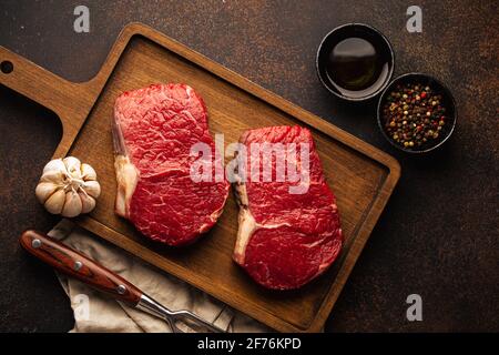 Zwei rohe Fleischsteaks auf Holzbrett Stockfoto