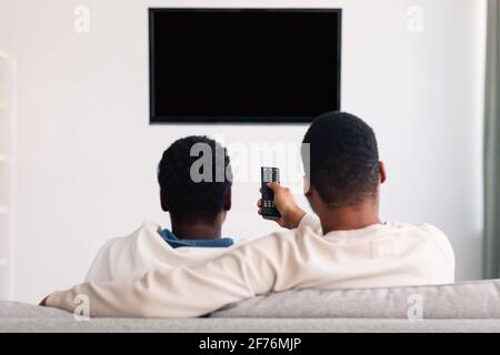 Schwarzes Paar beim Fernsehen und mit Fernbedienung Stockfoto