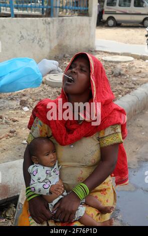 Neu-Delhi, Indien. April 2021. Ein Gesundheitsmitarbeiter, der persönliche Schutzausrüstung (PSA) trägt, sammelt Mundabstrichproben von einer Frau für den Coronavirus Covid-19 RT-PCR-Test an einer Straßenseite in der Nähe des Bahnhofs in Neu-Delhi.Indien verzeichnete den Höchststand von 103,558 Coronavirus-Infektionen und damit den höchsten seit Beginn der Coronavirus-Pandemie in Indien. (Foto von Naveen Sharma/SOPA Images/Sipa USA) Quelle: SIPA USA/Alamy Live News Stockfoto