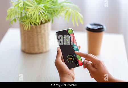 Schwarze Frau mit Smartphone, macht Online-Zahlungen Stockfoto