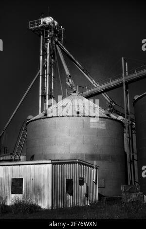 Getreidegerüst, Tanks, Gehweg und Plattform in Schwarz-Weiß vor einem klaren Himmel fotografiert. Gefunden in einer ländlichen Bauerngemeinschaft in Texas. Stockfoto