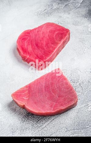 Zwei rohe Thunfisch-Steaks auf rustikalem Tisch. Weißer Hintergrund. Draufsicht Stockfoto