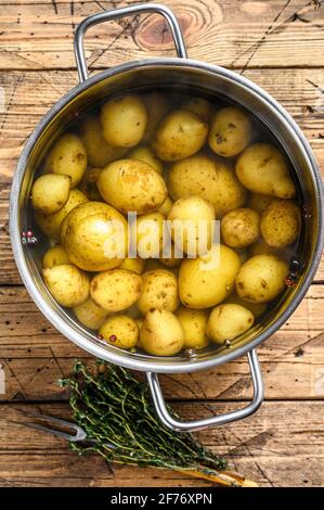 Gekochte Babykartoffeln in einem Topf. Holzhintergrund. Draufsicht Stockfoto