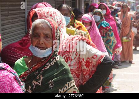 Frauen versammeln sich in einer Schlange, um Reis und Mehl vom Open Market Sale (OMS) in Modu Shohid, Sylhet, zu kaufen. Eine landesweite Sperrung wurde für 7 Tage verhängt. Bangladesch. Stockfoto