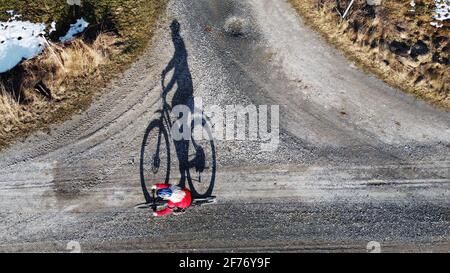 Luftaufnahme mit Drohne einer Radfahrerin auf der Straße mit Schatten Stockfoto