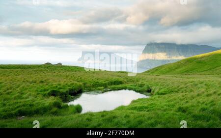 Lonely Tourist in der Nähe von kleinen See schaut auf nebligen Inseln im Atlantik von kalsoy Island, Färöer, Dänemark. Landschaftsfotografie Stockfoto