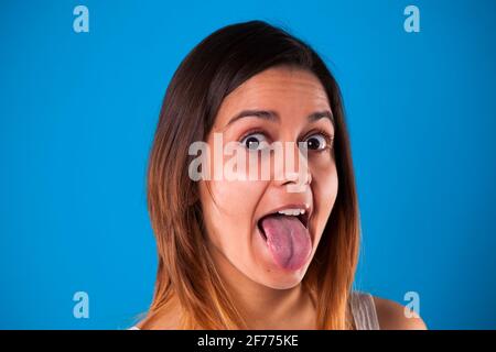 Frau mit der Zunge aus mit einem blauen Hintergrund Stockfoto