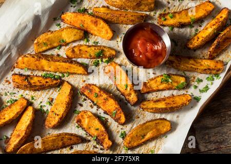 Hausgemachte, würzige Kartoffelkeile aus dem Ofen mit Ketchup Stockfoto